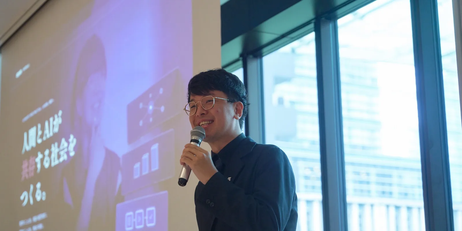 明るい会議室で、参加者に向かって笑顔で話す小澤健祐